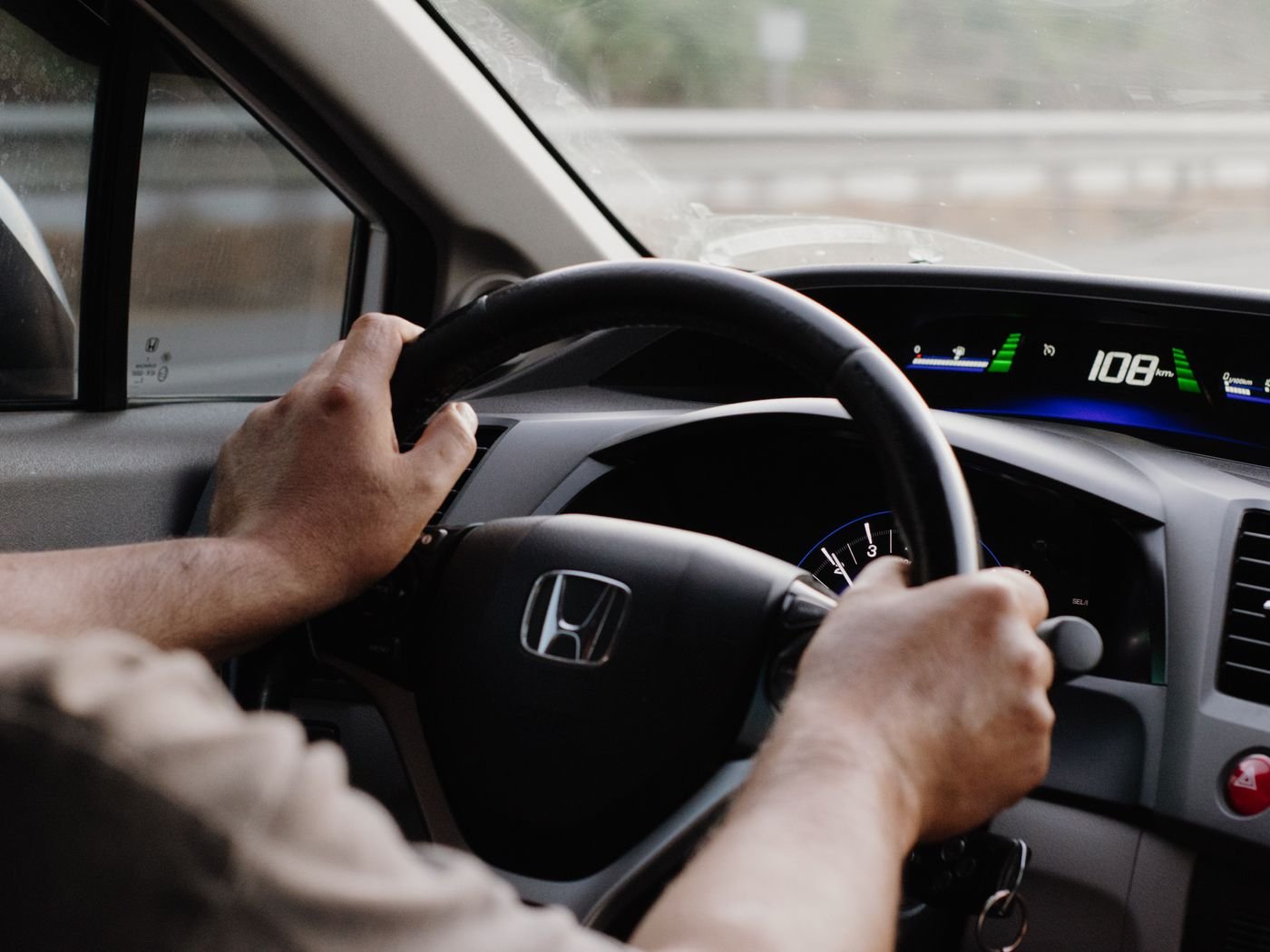 Driver steering a car with hands on the wheel